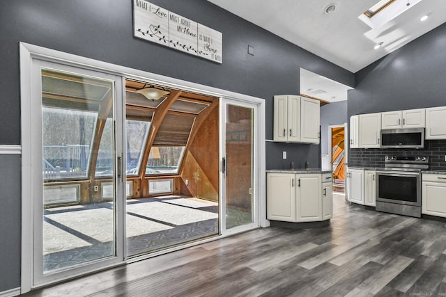 kitchen featuring decorative backsplash, white cabinets, appliances with stainless steel finishes, and a skylight