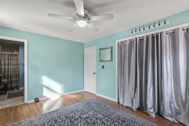 unfurnished bedroom featuring connected bathroom, a ceiling fan, baseboards, and wood finished floors