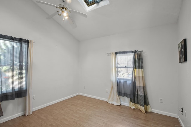 unfurnished room with vaulted ceiling with skylight, light wood-style flooring, baseboards, and ceiling fan