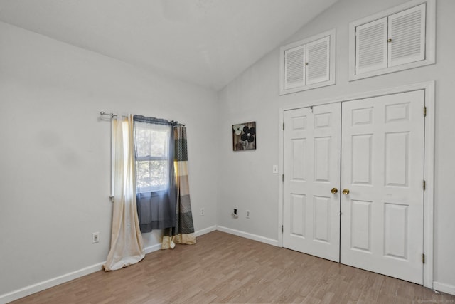 unfurnished bedroom with light wood-type flooring, baseboards, and vaulted ceiling