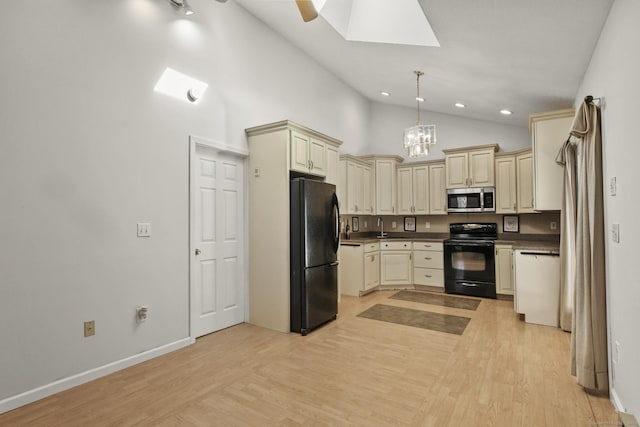 kitchen with light wood finished floors, a skylight, black appliances, dark countertops, and cream cabinets