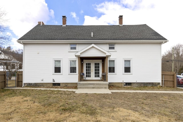 rear view of house featuring a lawn, french doors, fence, and a gate