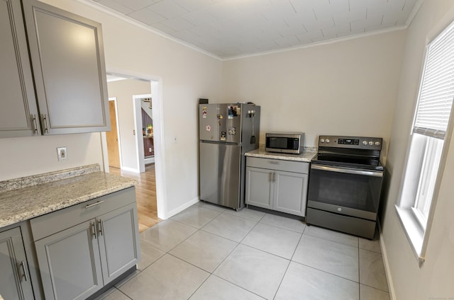 kitchen with baseboards, light tile patterned flooring, ornamental molding, gray cabinetry, and stainless steel appliances