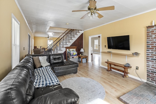 living area featuring baseboards, ceiling fan, stairway, ornamental molding, and wood finished floors