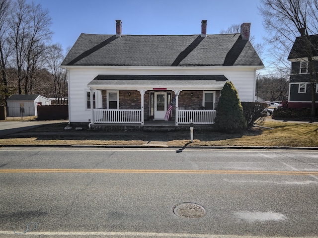 bungalow-style home with covered porch, a chimney, and roof with shingles