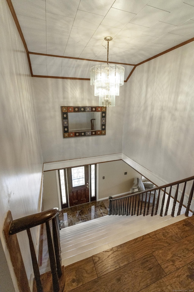 foyer featuring an inviting chandelier, crown molding, stairway, and wood finished floors