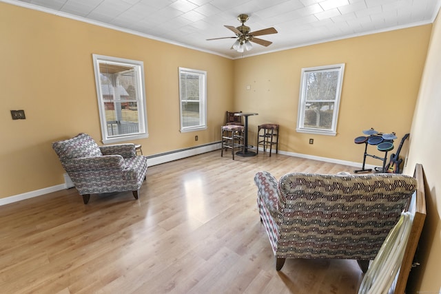 sitting room with a baseboard heating unit, crown molding, and a wealth of natural light