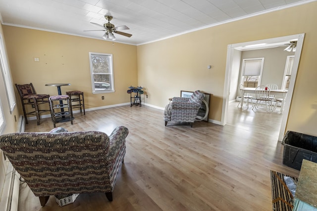 sitting room featuring baseboards, plenty of natural light, wood finished floors, and crown molding