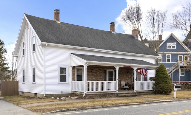 view of front facade featuring roof with shingles and covered porch