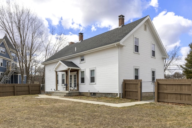 back of property with roof with shingles, a chimney, and fence