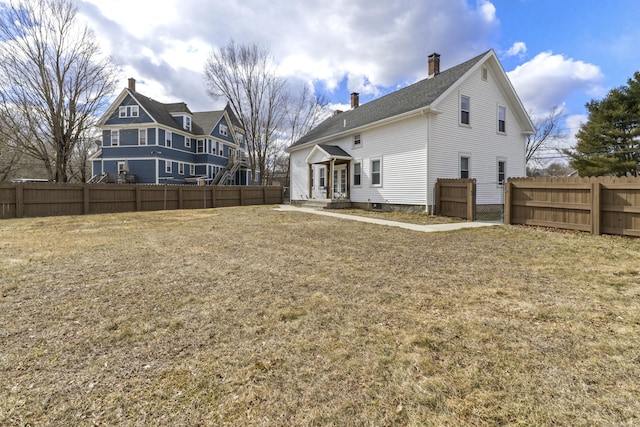 rear view of property featuring fence, a lawn, and a chimney