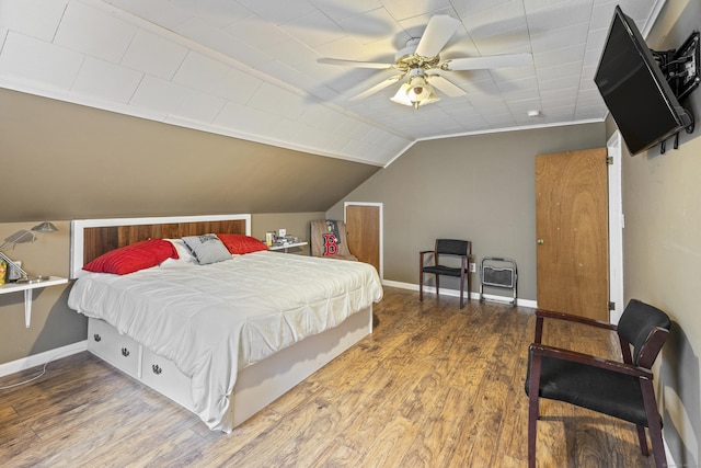 bedroom featuring a ceiling fan, vaulted ceiling, wood finished floors, and baseboards