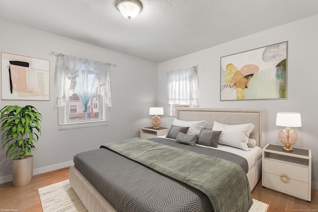 bedroom with baseboards, a textured ceiling, and wood finished floors