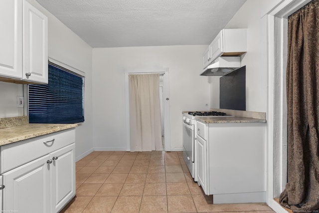 kitchen featuring white gas stove, white cabinetry, light countertops, and under cabinet range hood