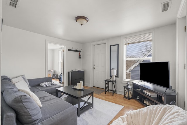 living room featuring baseboards, visible vents, and light wood-type flooring