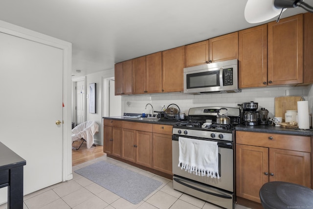 kitchen featuring a sink, dark countertops, decorative backsplash, and stainless steel appliances