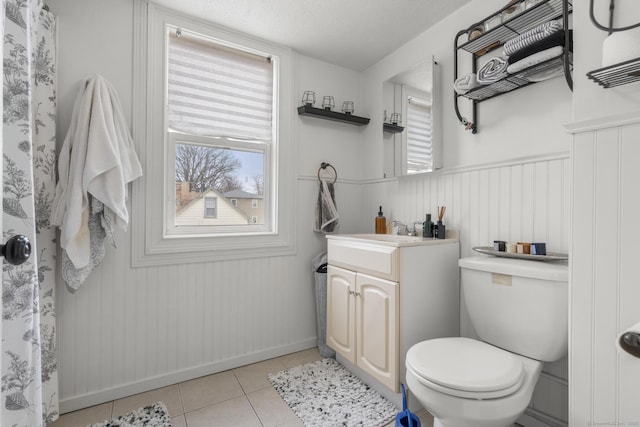 full bath featuring vanity, a wainscoted wall, tile patterned flooring, a textured ceiling, and toilet