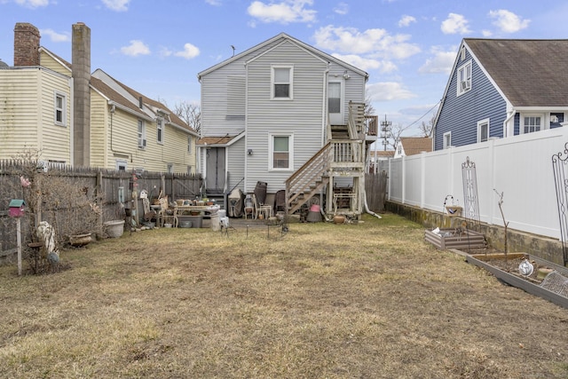 back of house featuring a yard, a vegetable garden, a fenced backyard, and stairs