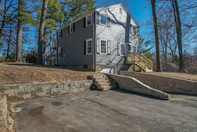 view of side of property featuring stairway, a garage, and driveway