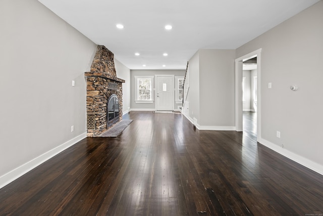 unfurnished living room featuring a fireplace, baseboards, and dark wood-style flooring