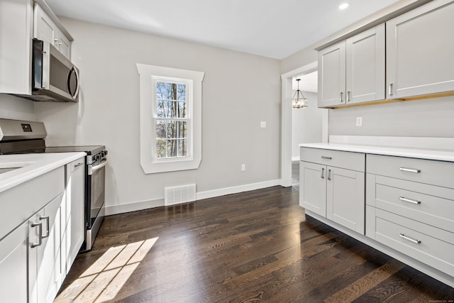 kitchen with visible vents, baseboards, dark wood finished floors, light countertops, and stainless steel appliances