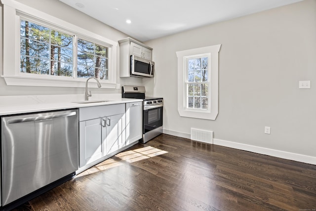 kitchen with visible vents, baseboards, dark wood finished floors, appliances with stainless steel finishes, and a sink