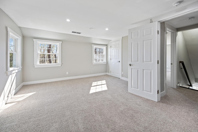 interior space with multiple windows, light colored carpet, visible vents, and baseboards