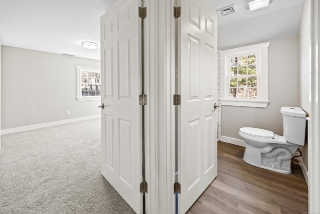 bathroom featuring visible vents, toilet, baseboards, and wood finished floors