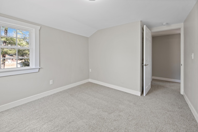 unfurnished bedroom featuring light colored carpet, baseboards, and vaulted ceiling