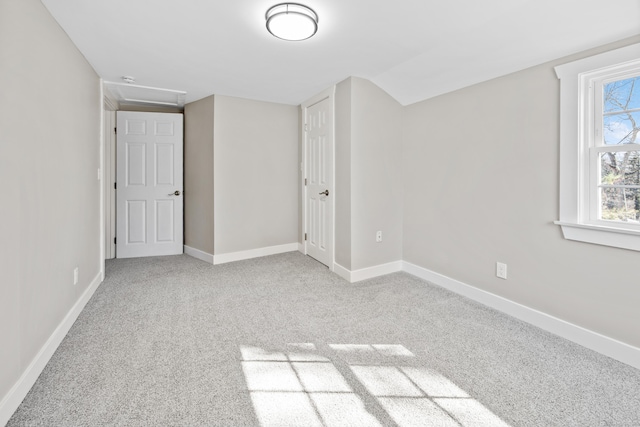 unfurnished bedroom featuring vaulted ceiling, baseboards, and carpet floors