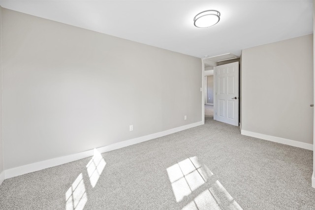 spare room with attic access, carpet flooring, and baseboards