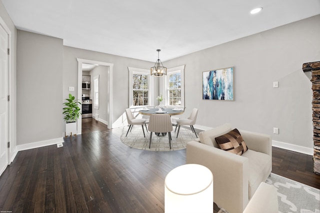 dining area featuring a chandelier, dark wood-type flooring, and baseboards