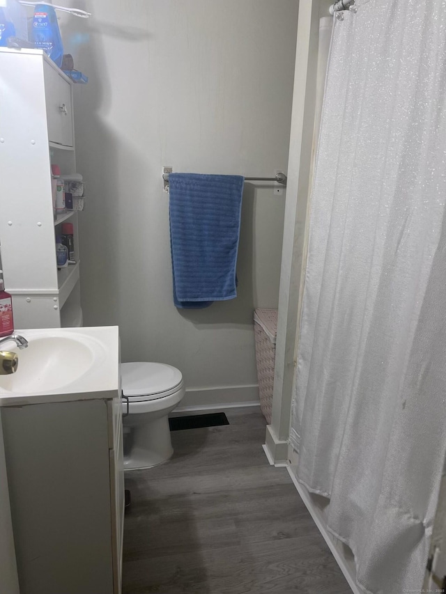 full bath featuring toilet, curtained shower, wood finished floors, baseboards, and vanity