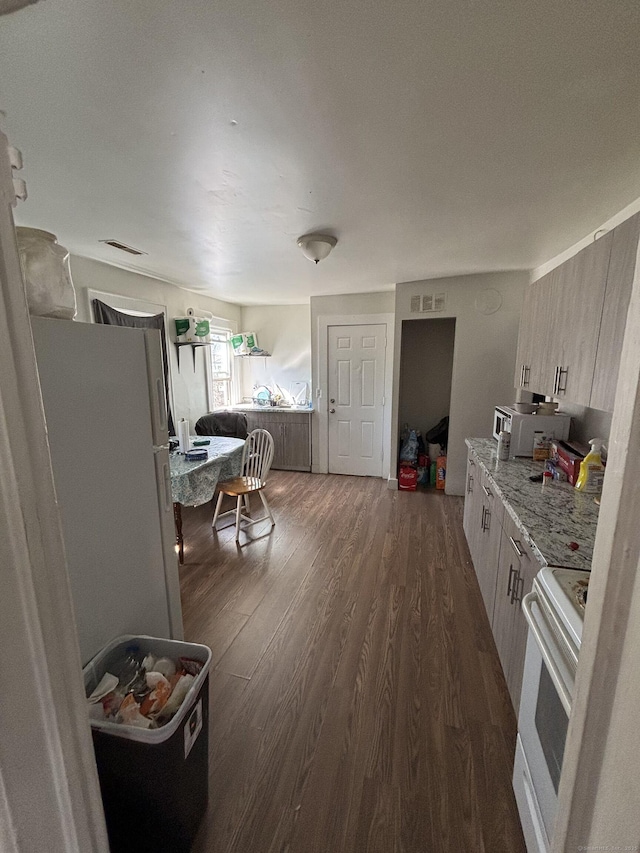 kitchen featuring light stone counters, dark wood-style flooring, visible vents, and white electric range oven