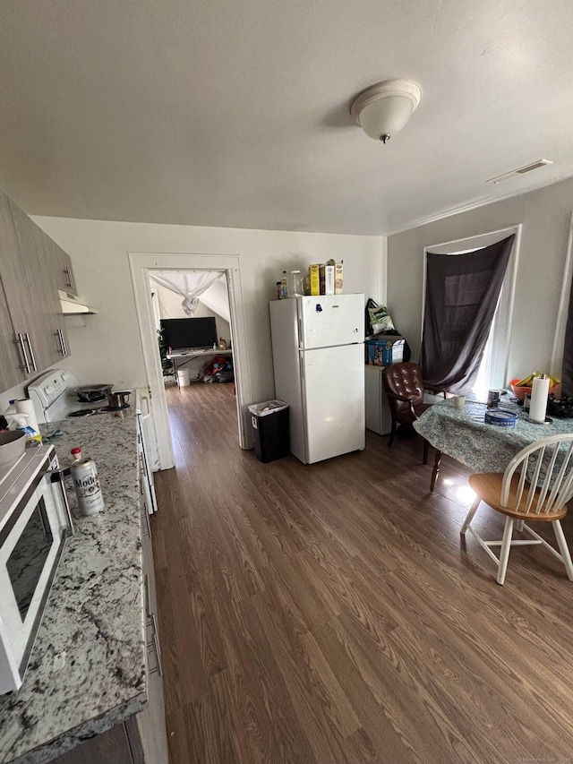 kitchen with visible vents, light stone counters, dark wood-style floors, freestanding refrigerator, and range