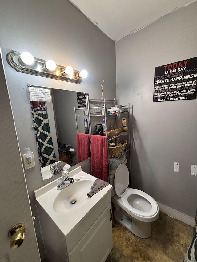 bathroom featuring baseboards, toilet, and vanity