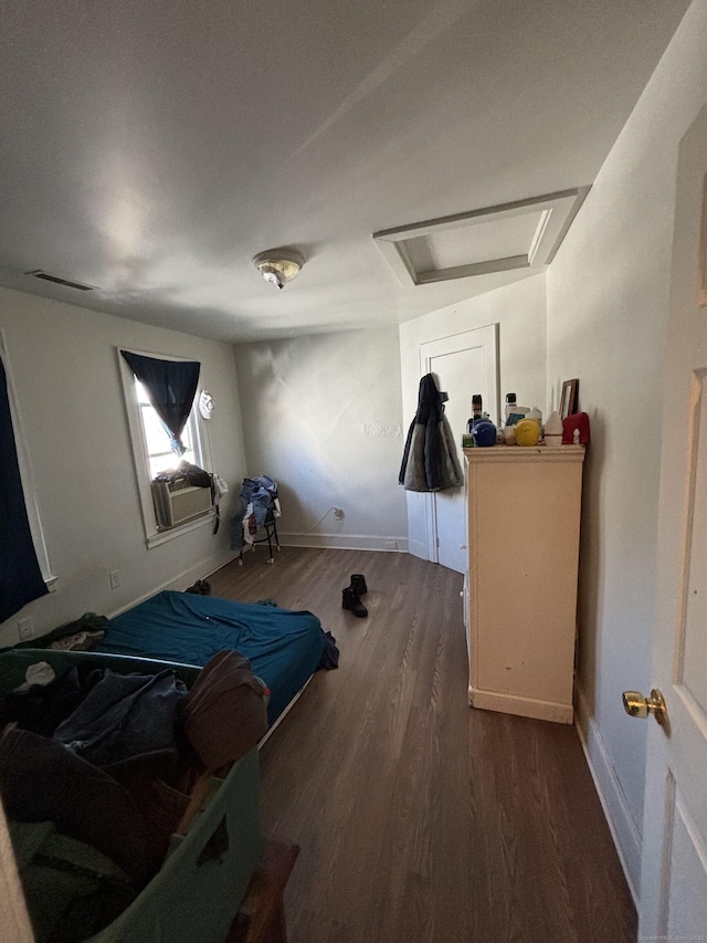 bedroom featuring cooling unit, wood finished floors, visible vents, baseboards, and attic access