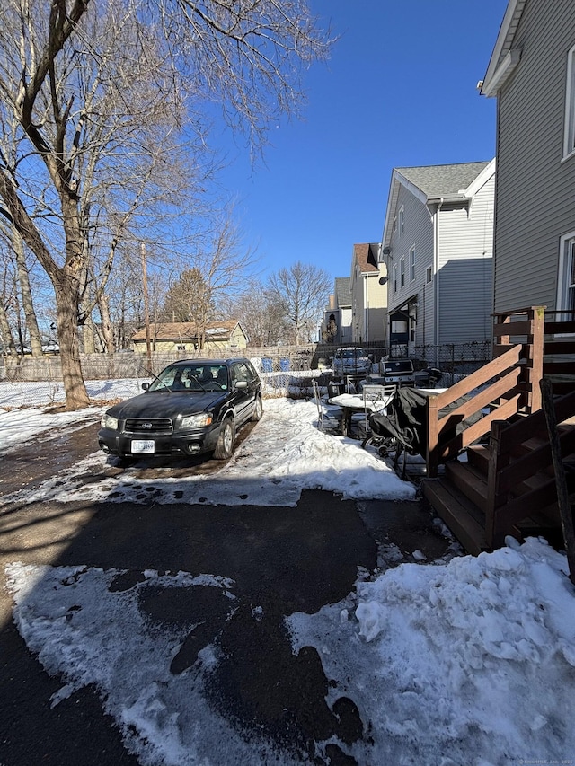 snowy yard featuring a residential view and fence