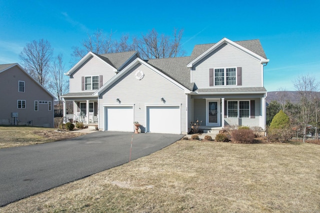 traditional-style home featuring a garage, covered porch, driveway, and a front yard