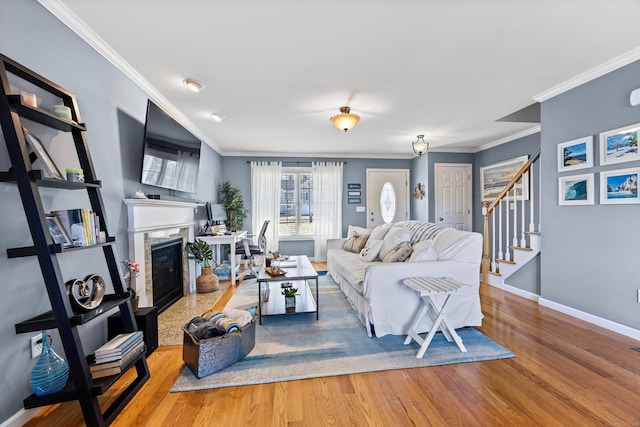 living room with stairway, wood finished floors, baseboards, a high end fireplace, and ornamental molding