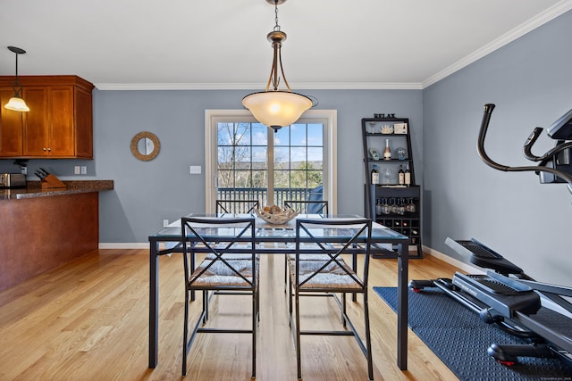 dining room featuring crown molding, light wood-style floors, and baseboards