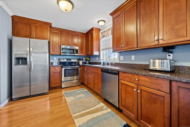 kitchen featuring a sink, brown cabinetry, light wood finished floors, and stainless steel appliances