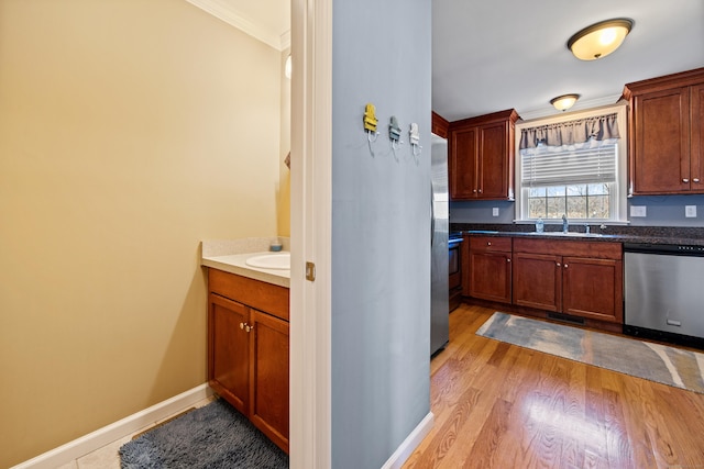 kitchen featuring baseboards, light wood-type flooring, ornamental molding, stainless steel dishwasher, and a sink