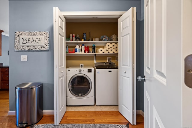 laundry room with washer and dryer, baseboards, laundry area, and light wood finished floors