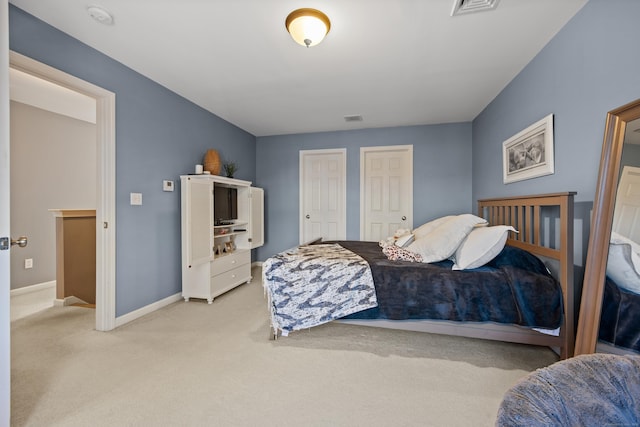 bedroom featuring light carpet, visible vents, two closets, and baseboards