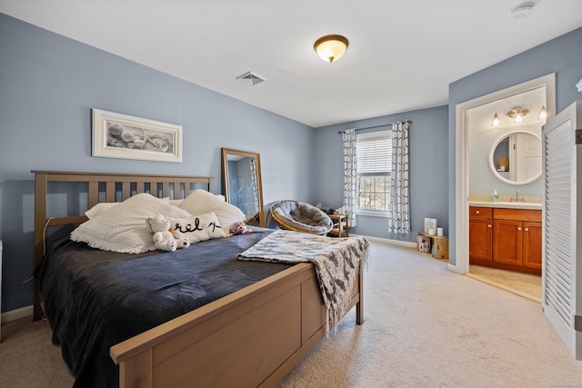 bedroom with visible vents, baseboards, light colored carpet, ensuite bathroom, and a sink