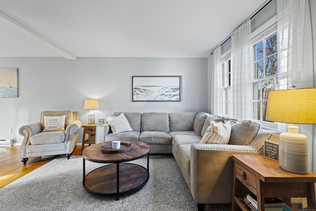 living area with beamed ceiling, wood finished floors, and a baseboard radiator