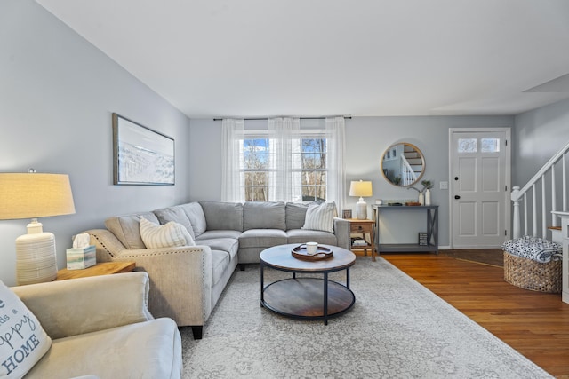 living room with baseboards, wood finished floors, and stairs