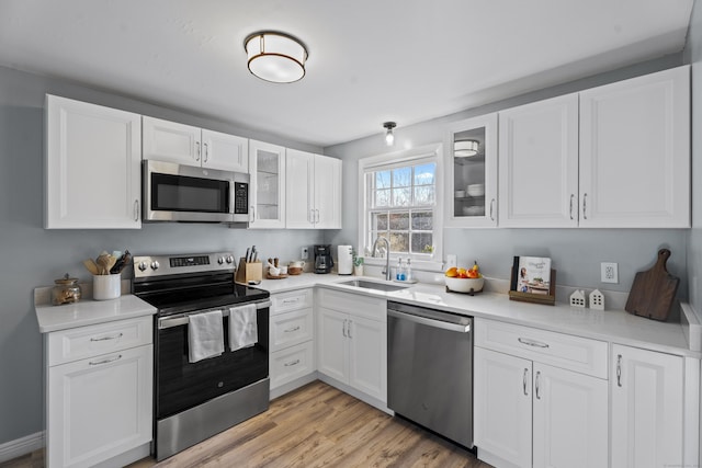 kitchen with white cabinets, stainless steel appliances, glass insert cabinets, and a sink