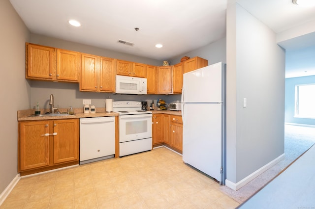 kitchen with white appliances, baseboards, visible vents, and a sink